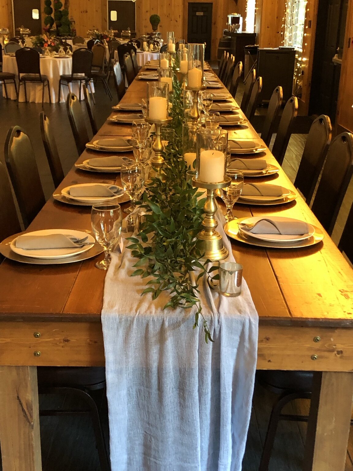 Long wooden dining table styled with greenery, candles and neutral place settings