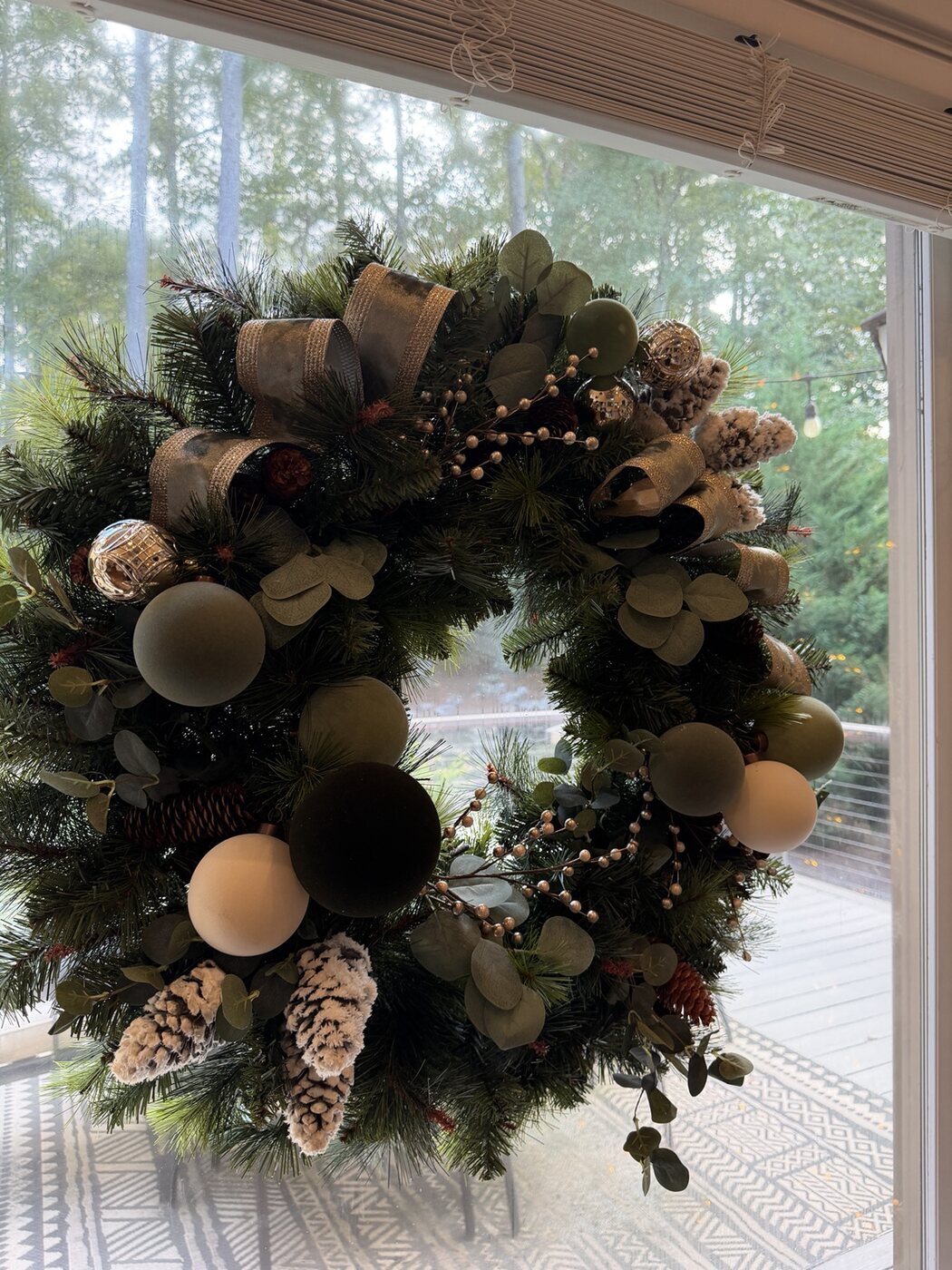 Christmas wreath styled with sage ornaments, eucalyptus, pinecones and ribbon